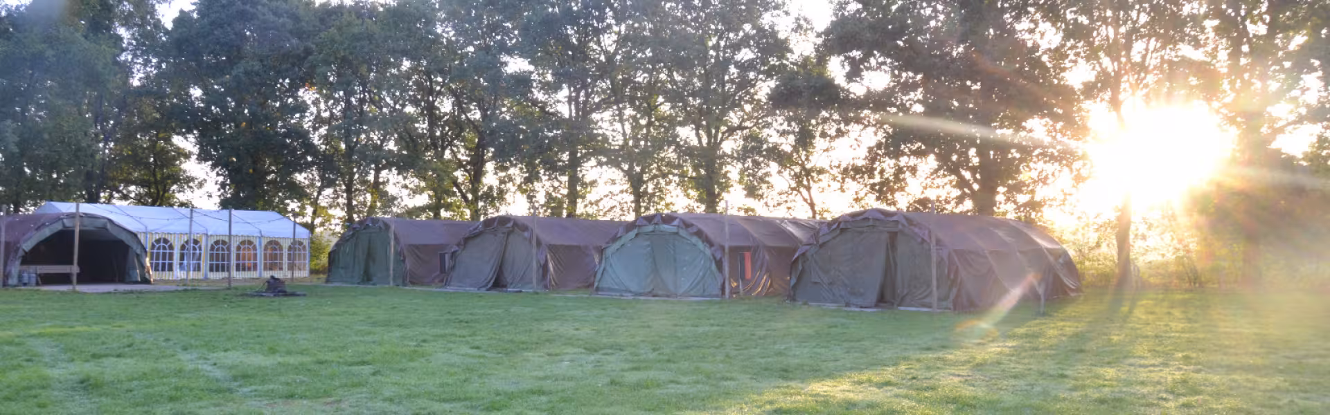 Rij tenten op een grasveld bij zonsopgang