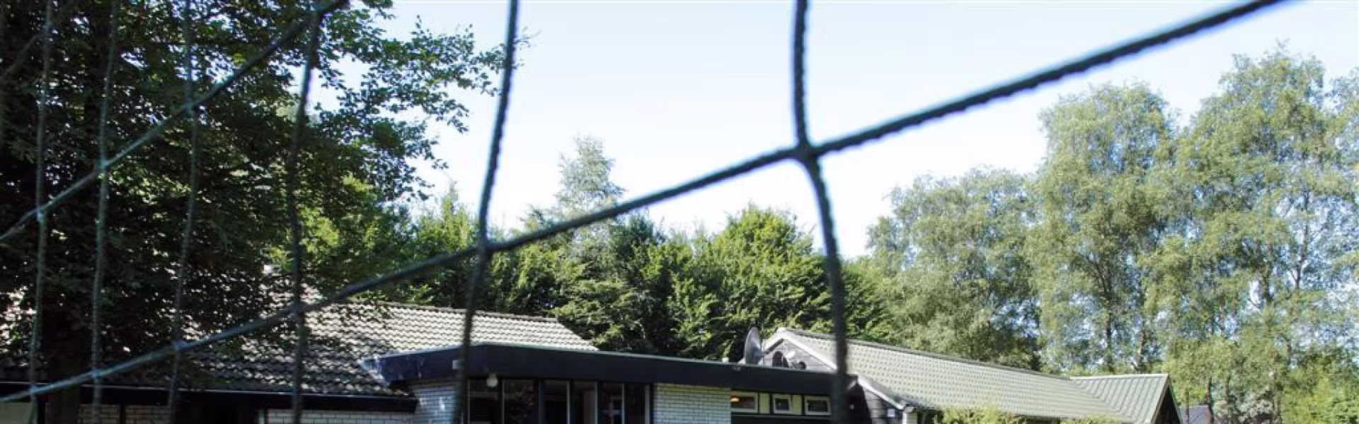 Kampgebouw achter een sportveld met net