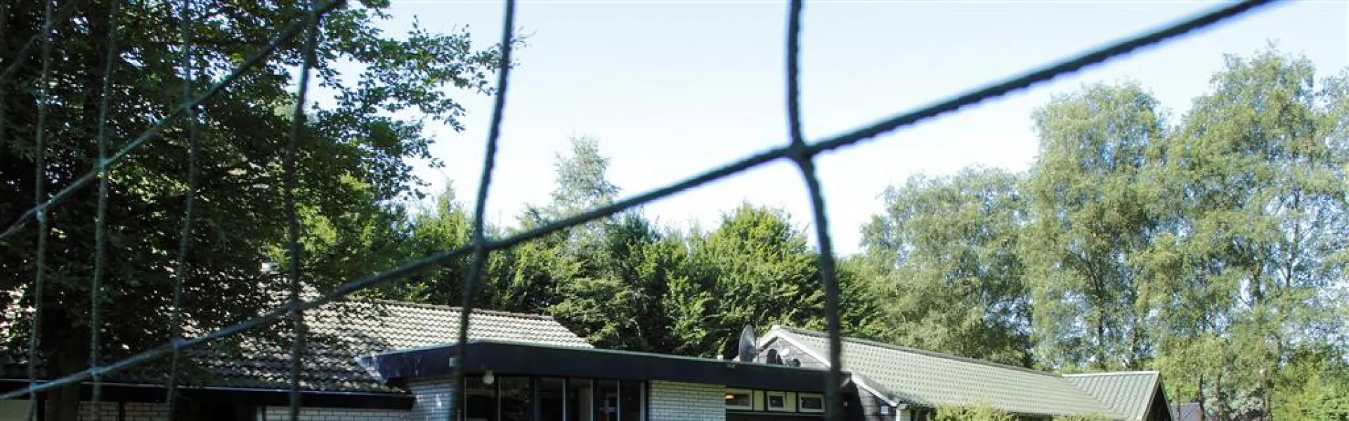 Kampgebouw achter een sportveld met net