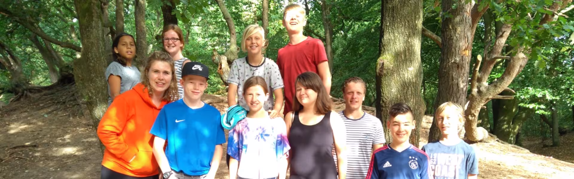 Groep deelnemers poseert tussen de bomen