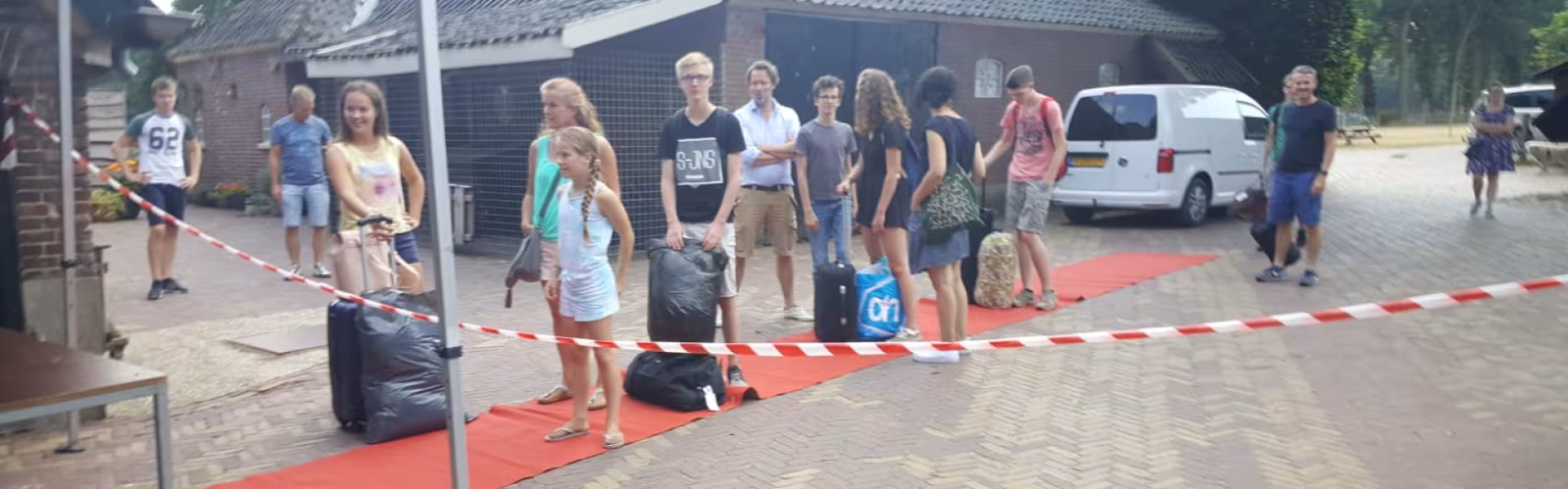 Deelnemers met bagage lopen over een rode loper
