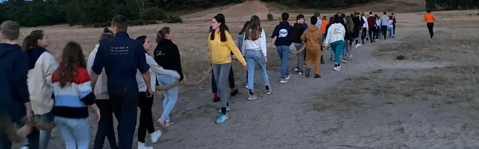 Deelnemers lopen over de zandvlakte bij schemer