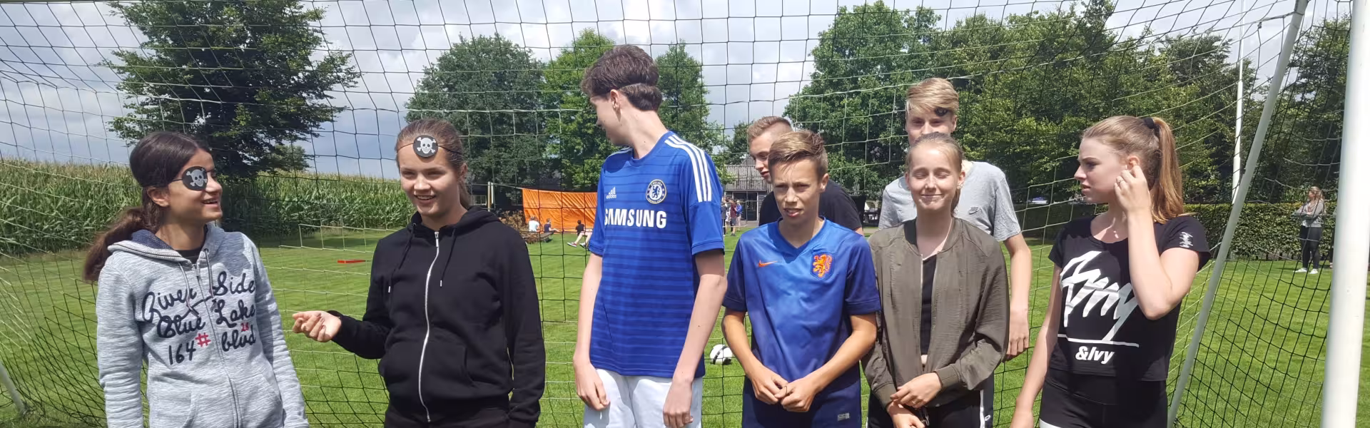 Deelnemers staan bij het doel op het sportveld