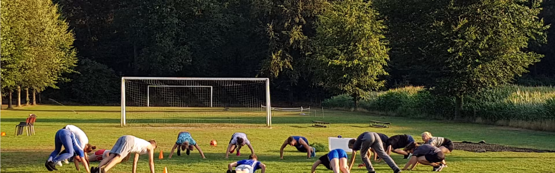 Deelnemers doen oefeningen op een sportveld