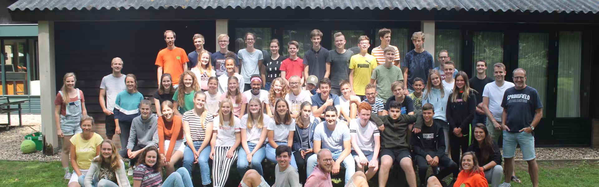 Grote groepsfoto van deelnemers voor het kampgebouw