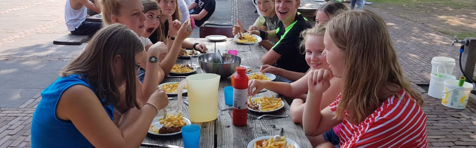 Deelnemers eten samen aan picknicktafels