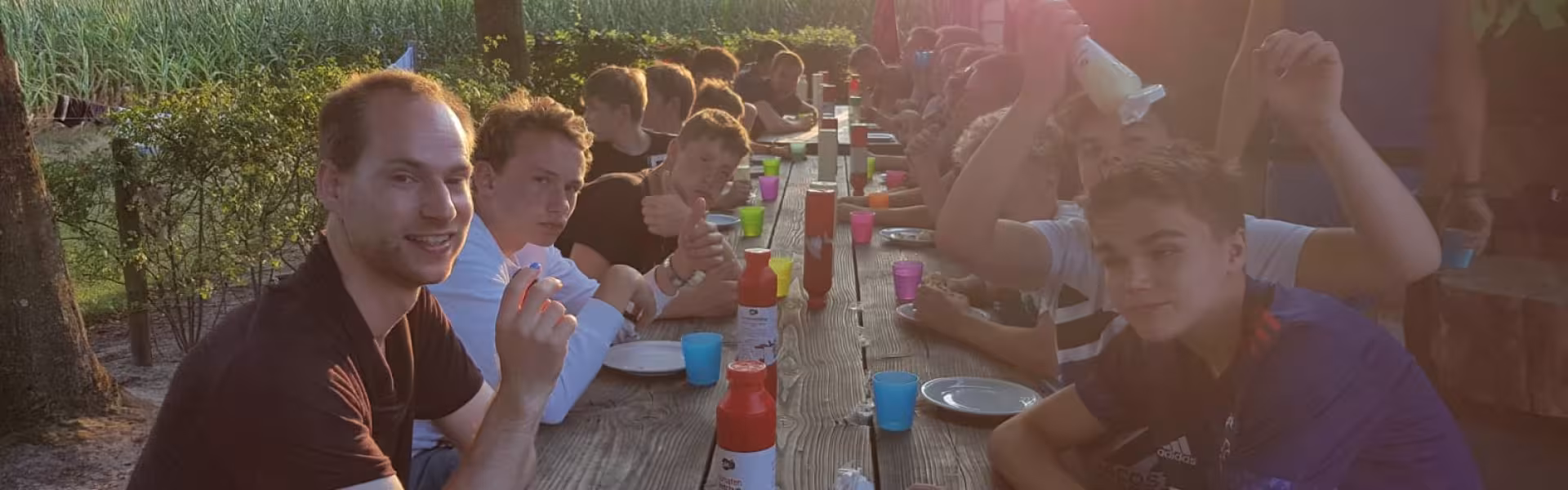 Deelnemers eten aan een tafel in de avondzon