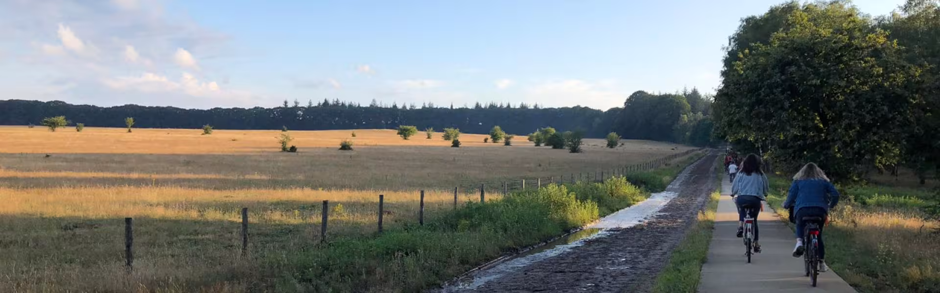 Fietsers op een landweg onder een bewolkte lucht