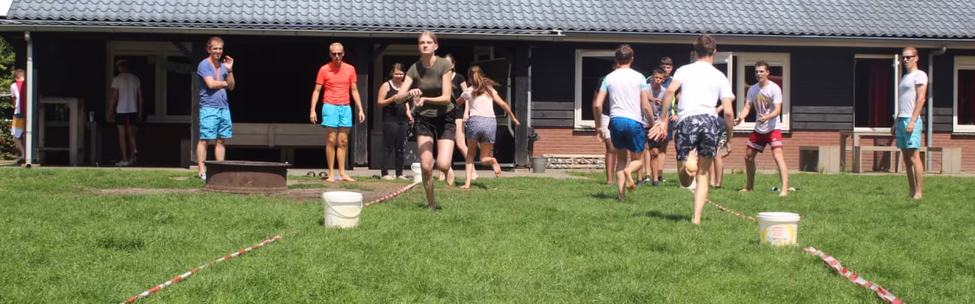 Deelnemers spelen een spel op het grasveld bij het gebouw