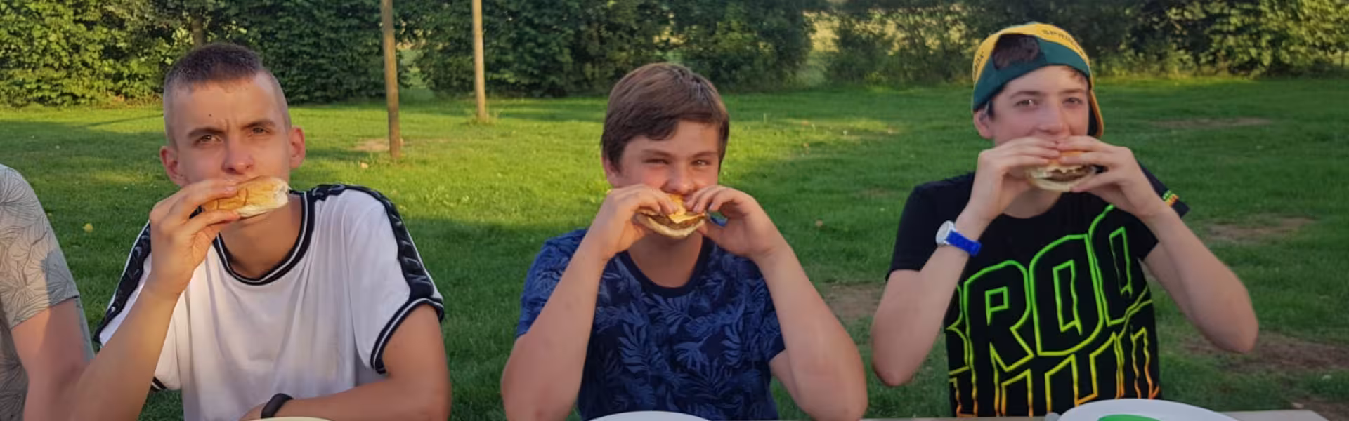 Deelnemers eten een broodje aan tafel buiten