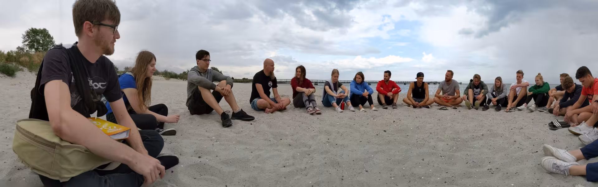 Deelnemers zitten op een rij in het zand