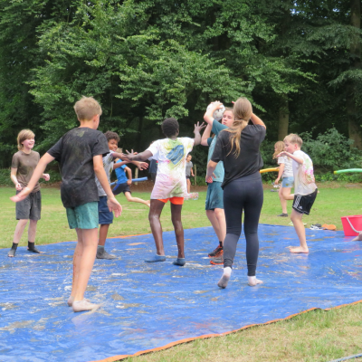 Deelnemers spelen op een blauw zeil met water