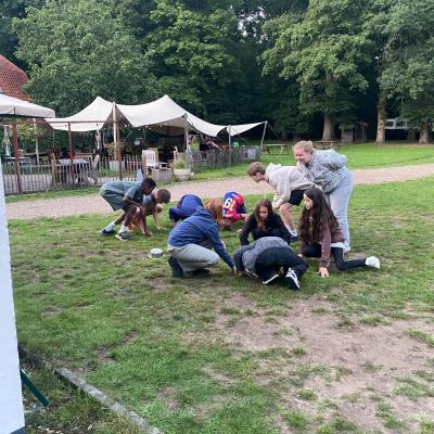 Deelnemers zitten in het gras bij de tent