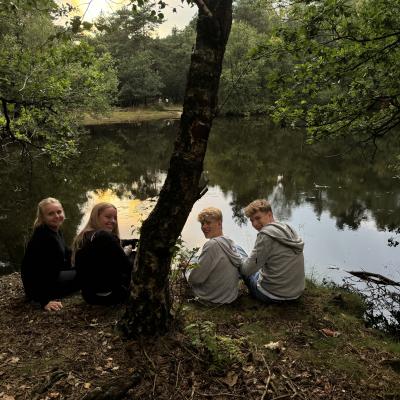 Deelnemers rond een kampvuur in het bos