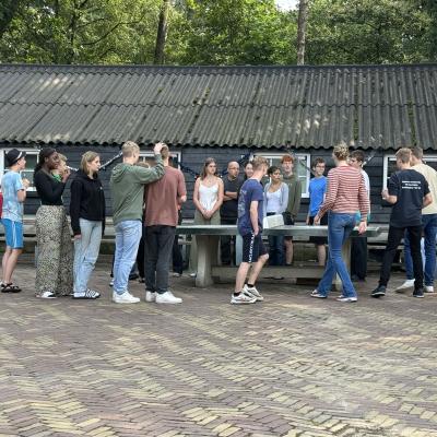 Deelnemers staan in een rij bij het kampgebouw