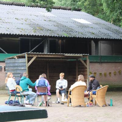 Deelnemers zitten voor een schuur