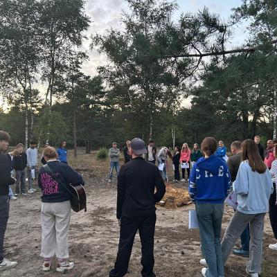 Deelnemers staan in een kring op de zandvlakte