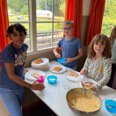 Kinderen aan tafel met een pan pannenkoeken