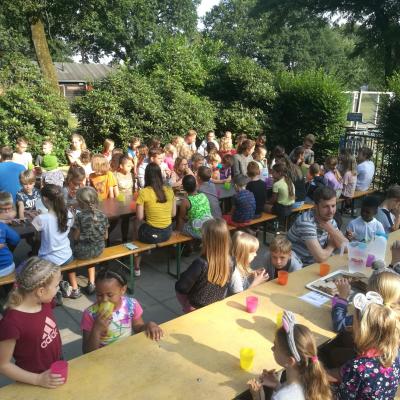 Deelnemers aan lange tafels onder een luifel
