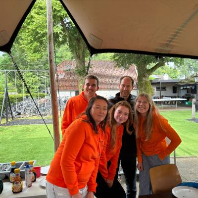 Deelnemers in oranje truien onder een luifel