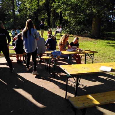 Deelnemers bij picknicktafels in de schaduw