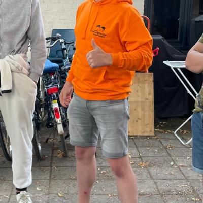 Deelnemer in een oranje trui op het terras